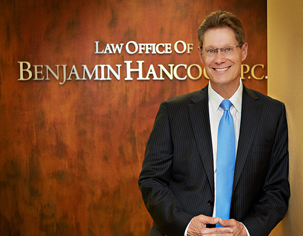 Benjamin Hancock Attorney standing in office in front of offiice sign